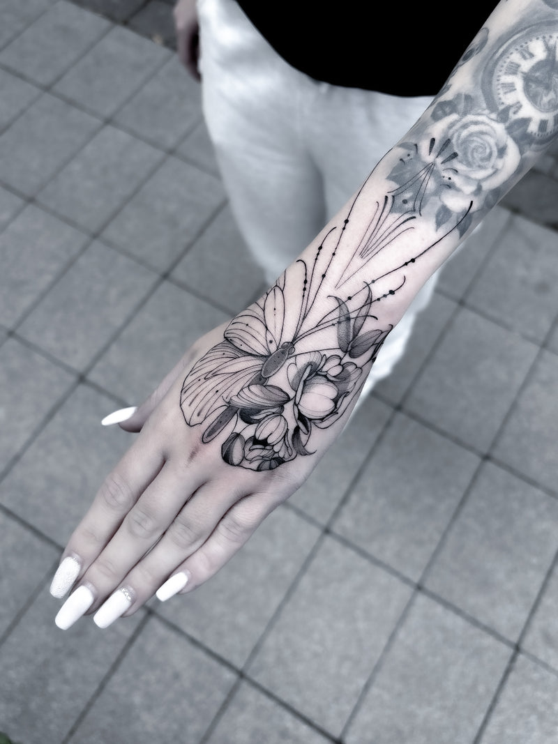 Fine line floral hand and forearm tattoo by Inko