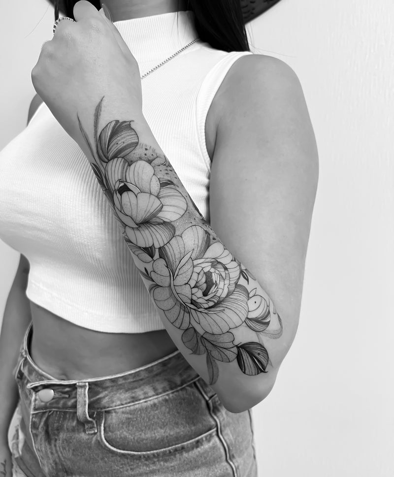 Fine line floral forearm tattoo by Inko