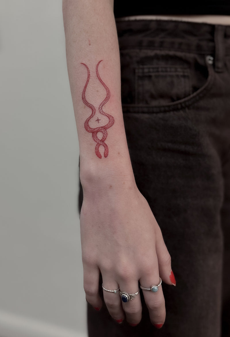 Red fine line wrist tattoo by Inko